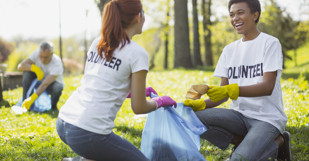 Two individuals picking up litter with shirts that read 